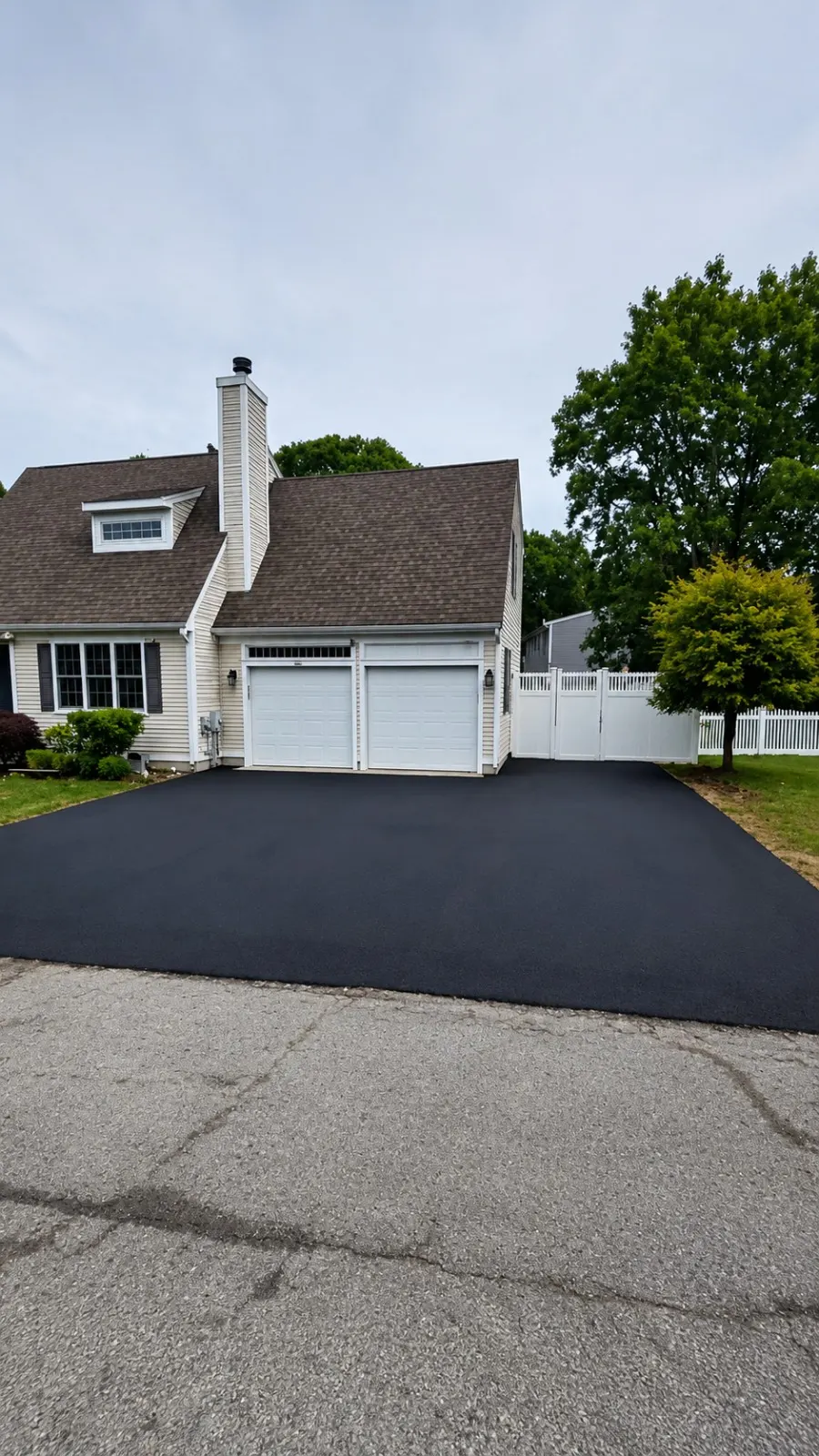 New black asphalt driveway finished in front of a two-car garage