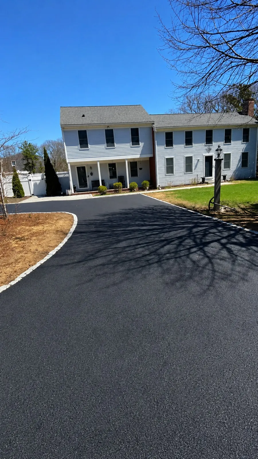 Large finished asphalt driveway with curved stone edging at a residence